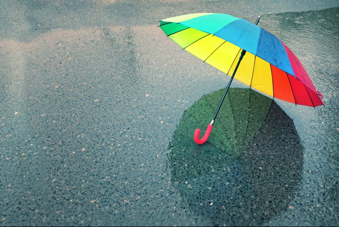 Colorful umbrella sitting on wet pavement