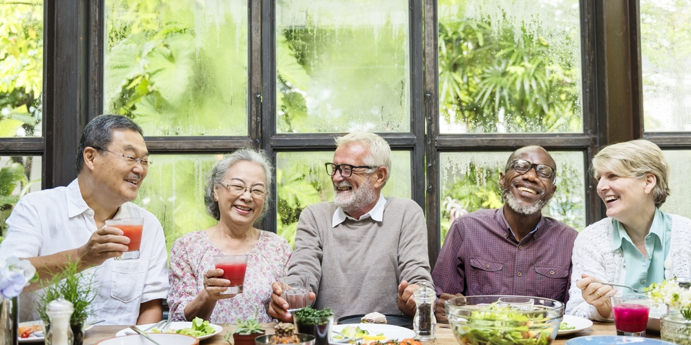 Group of elder adults enjoying a meal and laughing